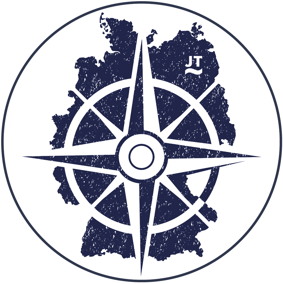 Eine marineblaue Windrose auf einer Silhouettenkarte von Deutschland, mit den Initialen "JT" im nordöstlichen Bereich, alles innerhalb eines kreisförmigen Rahmens. Jörg Tuschling - Interim Operations Management
